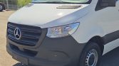 Front view of a white Mercedes-Benz van showing the black grille, emblem, and headlight assembly.