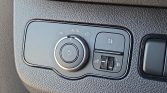Car headlight control panel: rotary dial for lights (Auto, off, parking, headlights), plus a fog-light button and a beam-level/adjustment dial on a textured dashboard panel.