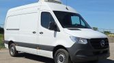 White Mercedes-Benz cargo van with a rooftop refrigeration unit parked on a paved lot.
