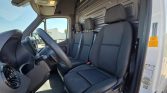 Driver and two passenger seats in a white delivery van, viewed from the open front door with steering wheel and dashboard visible.