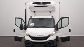 Front view of a white Iveco refrigerated truck with both cab doors open and a Thermo King unit on top, shown indoors in a studio setting.