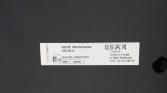 Underrun protection label on a dark surface showing E13 approval mark, serial number 22054015278, and DBAR Cargo label with contact info (Germany).