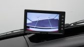 Dashboard-mounted display showing the car's rearview camera feed with green guiding lines for parking.