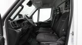 Interior of a white van cabin showing the steering wheel, dashboard, and three black fabric front seats from the passenger side angle