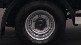 Close-up of a vehicle wheel: silver steel rim with lug nuts and a black tire.