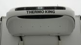 Front view of a Thermo King refrigerated unit mounted on a white semi-trailer, showing the brand name and air grille on top of the cab area