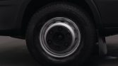 Close-up of a vehicle wheel: steel rim with lug nuts and tire on a white van body underneath the fender