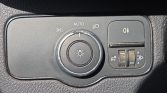 Headlight control panel in a car: dial set to Auto with headlight symbol, right-side button for fog lights, plus a small roller switch with 0–3 indicators for dimming/adjustment.