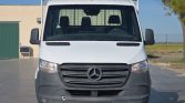 Front view of a white Mercedes-Benz cargo van parked outdoors, showing grille, headlights, and side mirrors at the front.