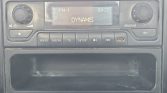 Car stereo face with FM1 display showing DYNAMIS and time 09:32, with radio buttons below and a large empty tray area below the controls.