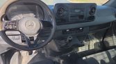 Driver's cockpit of a vehicle with a black steering wheel showing the Mercedes emblem, dashboard, and manual gear lever visible near the center console.