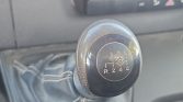 Close-up of a six-speed manual gear shift knob showing the shift pattern (R 1 2 3 4 5 6) inside a car interior.