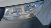 Close-up of a car’s headlight on a white vehicle, showing a clear lens and amber turn signal.