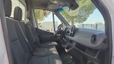 Interior of a white van showing the front three seats and gray upholstery with dashboard visible