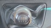 Six-speed manual gear shift knob with reverse, surrounded by a black leather boot with visible stitching