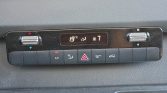 Vehicle climate control panel: digital display shows 19°C and fan level 7, with two side dials for temperature control and a row of buttons below (A/C, defrost, hazard, etc.).