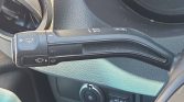 Close-up of a car's windshield wiper control stalk on the steering column, showing front/rear wiper and washer icons and settings