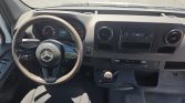 Interior of a Mercedes Sprinter van: steering wheel, dashboard, and manual gear shift visible from the driver’s seat