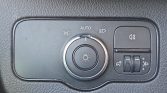Car headlight control panel with a circular dial set to Auto, and adjacent fog light and brightness adjustment switches on the right side.