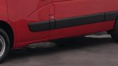 Red van side view with black protective molding along the lower door, wheel at left, parked on pavement.