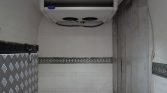 Refrigerated trailer interior with a ceiling cooling unit labeled Carrier, metal walls, and diamond-plate floor.