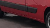 Red van side with black protective molding along the lower door panel.