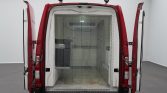 Rear of a red cargo van with both doors wide open, revealing an empty insulated cargo space with a diamond-plate metal threshold at the doorway.