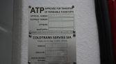 Two metal plaques mounted on a white textured wall; top plaque says ATP Approved for Transport of Perishable Foodstuffs with approval and equipment numbers, bottom plaque shows Coldtrans Serviss SIA details.