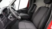 Front interior of a red van showing the steering wheel, dashboard, and two front seats (driver and passenger).