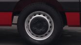 Close-up of a car wheel on a red vehicle, showing a black center hubcap and a silver rim with circular holes around it.