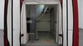 Open rear of a red van showing the cargo area with a diamond-plate floor, metal bulkhead, and hanging translucent curtains.