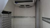Empty trailer cargo area with a ceiling air conditioner unit and metal E-track rails along the walls in a parked trailer.