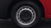 Close-up of a car wheel: steel rim with black center cap on a red vehicle, resting on a dark surface