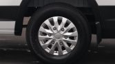 Close-up of a silver hubcap wheel and black tire on a white vehicle, showing the wheel well and fender edge.