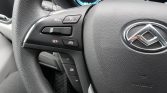Close-up of a car steering wheel with cruise control buttons (RES+, SET, cancel) and an OK arrow pad; dashboard visible in the background.