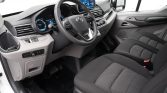 Interior view of a modern vehicle showing the steering wheel, digital instrument cluster, central touchscreen, and front seats with dotted fabric upholstery.