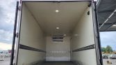 Empty white cargo trailer interior with sidewall rails and diamond plate at the rear, doors open for loading.