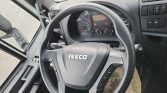 Steering wheel of an Iveco vehicle with instrument cluster and dashboard controls visible behind it, showing warning lights and gauges.
