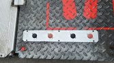 Diamond-plate metal floor with a light strip holding four circular buttons (black, red-brown, black, red-brown) and downward arrows beneath each one.