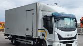 White Iveco Eurocargo delivery truck with an enclosed box trailer parked in an industrial lot