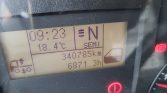 Dashboard display showing time 09:23, outside temp 18.4°C, compass heading N, and a distance/odometer reading with warning icons lit (red parking/brake indicators).