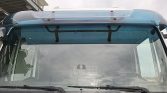 Front view of a blue truck cab, showing the windshield, wipers, and sky above