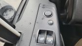 Driver-side door panel with two power window switches, a mirror-adjustment joystick, and a window-lock button.