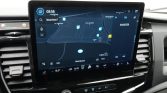 Car infotainment screen displaying a navigation map and route, with climate and media controls below the screen