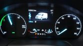 Digital instrument cluster: speedometer on the right, a left gauge, and a center screen showing a white van image with trip data and temperature; gear indicator PRNDL illuminated.