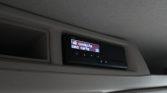 Overhead vehicle display panel with a small digital screen showing blue text mounted in the ceiling area of a car or bus.