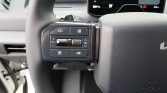 Steering wheel left-side control panel with multiple buttons and a small roller knob, used for cruise control and menu navigation