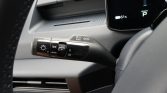 Close-up of a car’s multifunction stalk near the steering wheel showing headlight controls, including AUTO mode and fog light switch, with part of the dashboard in view.