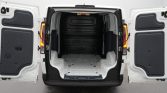 Open rear doors of a white cargo van showing an empty loading area with ribbed metal floor and black wall panels outside urban setting