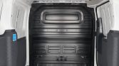 Interior of a white delivery van showing a black metal bulkhead barrier and empty cargo area